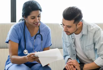 Young man and female doctor review medical chart together